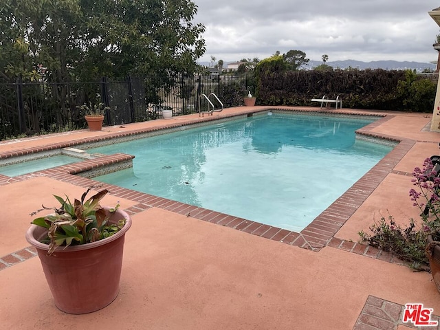 view of swimming pool featuring a patio and an in ground hot tub