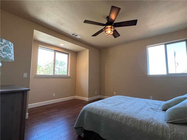 bedroom with a textured ceiling, ceiling fan, and dark hardwood / wood-style flooring