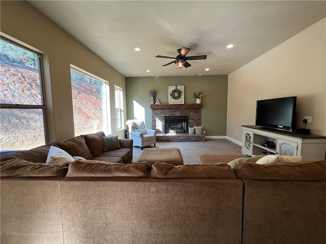 living room featuring a stone fireplace, a textured ceiling, light colored carpet, and ceiling fan