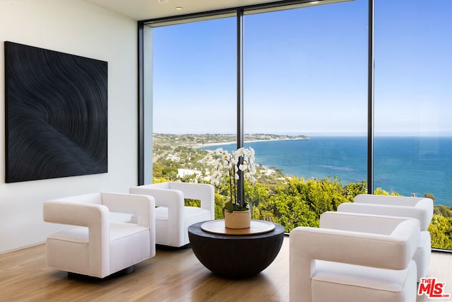 sitting room featuring a wall of windows, hardwood / wood-style flooring, and a water view