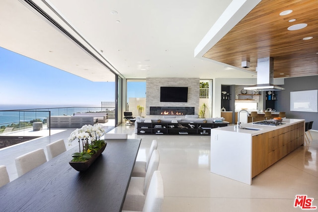 kitchen with sink, a fireplace, island exhaust hood, wooden ceiling, and stainless steel gas stovetop