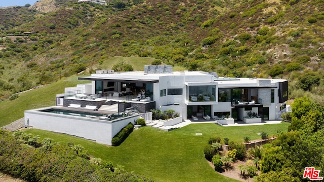 back of house with an outdoor kitchen, an outdoor hangout area, a bar, a patio area, and a lawn