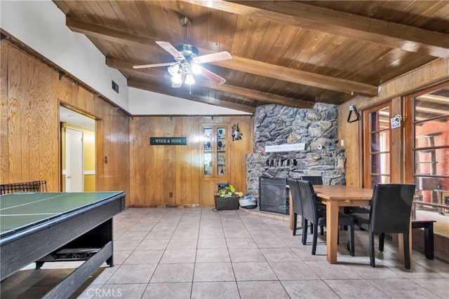 tiled dining space featuring lofted ceiling with beams, ceiling fan, wooden ceiling, and wood walls