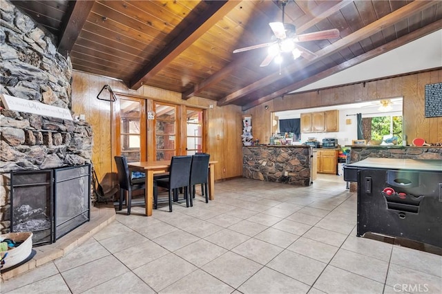 tiled dining area with a fireplace, lofted ceiling with beams, wooden walls, and wood ceiling