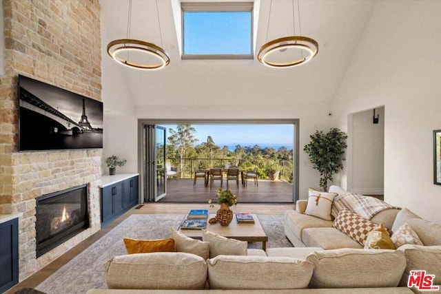 living room featuring high vaulted ceiling, a brick fireplace, and light hardwood / wood-style flooring