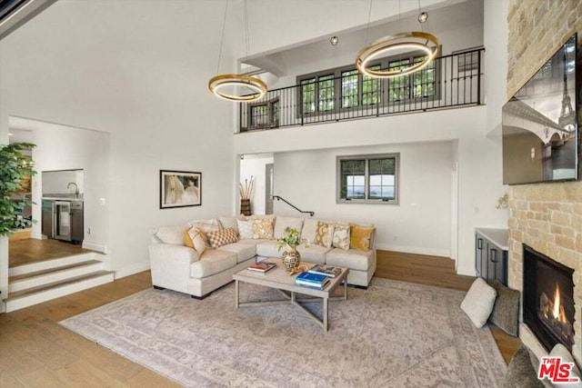 living room featuring hardwood / wood-style flooring, a fireplace, sink, and a high ceiling