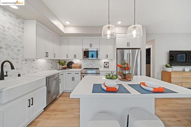 kitchen featuring pendant lighting, appliances with stainless steel finishes, white cabinetry, and a center island