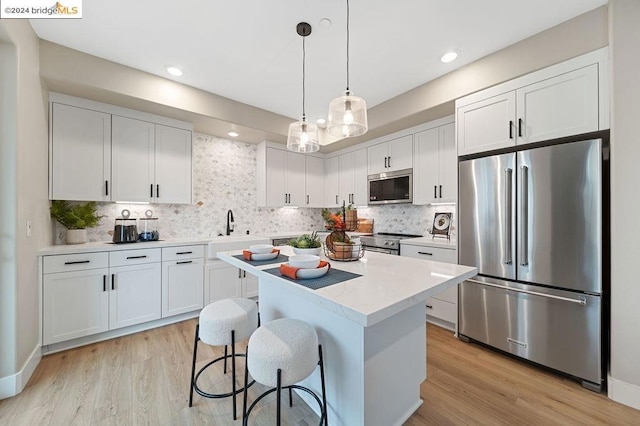 kitchen featuring decorative backsplash, white cabinets, pendant lighting, stainless steel appliances, and a center island