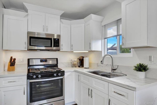 kitchen featuring sink, white cabinets, light stone counters, and stainless steel appliances