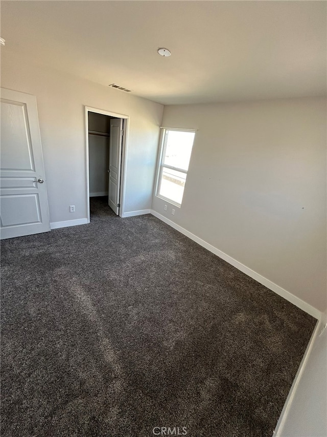 unfurnished bedroom with a closet and dark colored carpet