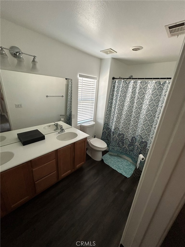 bathroom featuring curtained shower, hardwood / wood-style flooring, vanity, and toilet