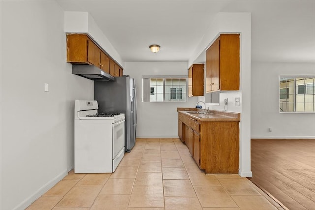 kitchen with stainless steel fridge with ice dispenser, sink, light tile patterned floors, and white gas range