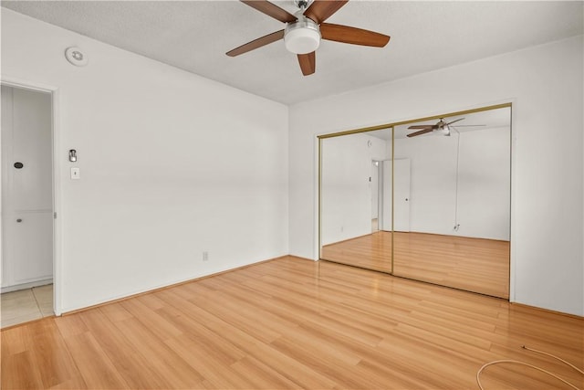 unfurnished bedroom with ceiling fan, a closet, and hardwood / wood-style floors