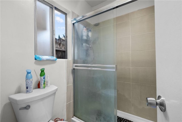 bathroom with a shower with shower door and toilet