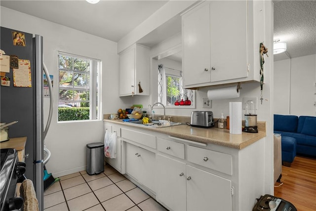 kitchen with sink, a textured ceiling, white cabinets, and light tile patterned flooring