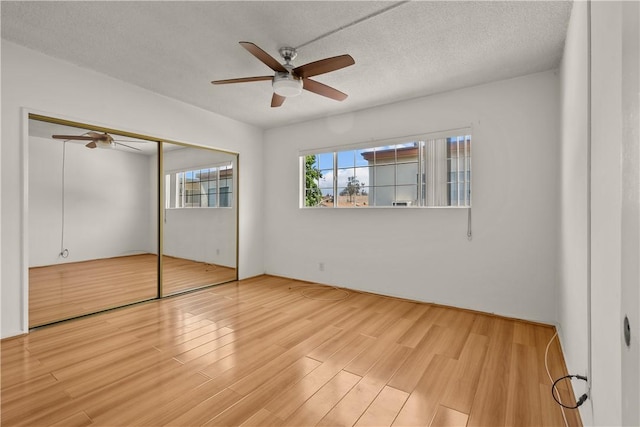 unfurnished bedroom featuring ceiling fan, a textured ceiling, a closet, and light hardwood / wood-style flooring