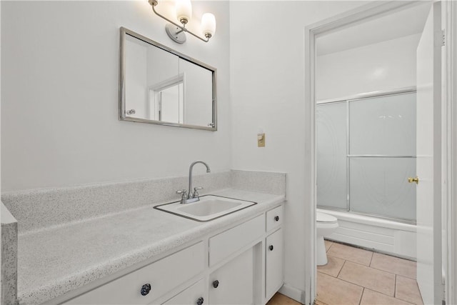 full bathroom with tile patterned floors, combined bath / shower with glass door, vanity, and toilet