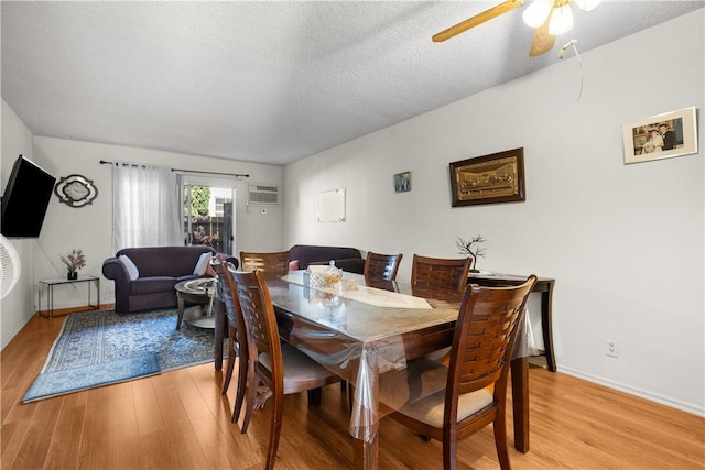 dining space with ceiling fan, a wall mounted AC, a textured ceiling, and light hardwood / wood-style floors