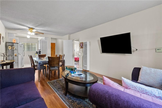 living room with hardwood / wood-style flooring, a textured ceiling, and ceiling fan