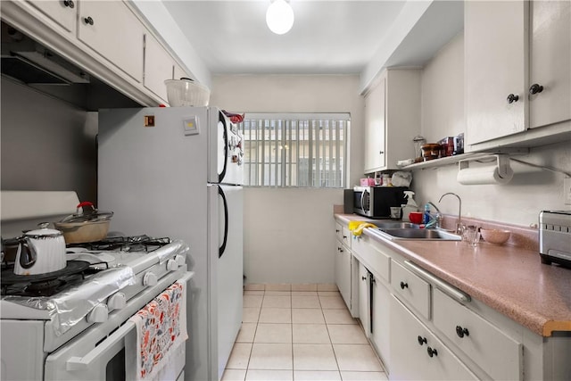 kitchen with white gas stove, sink, white cabinets, and light tile patterned flooring