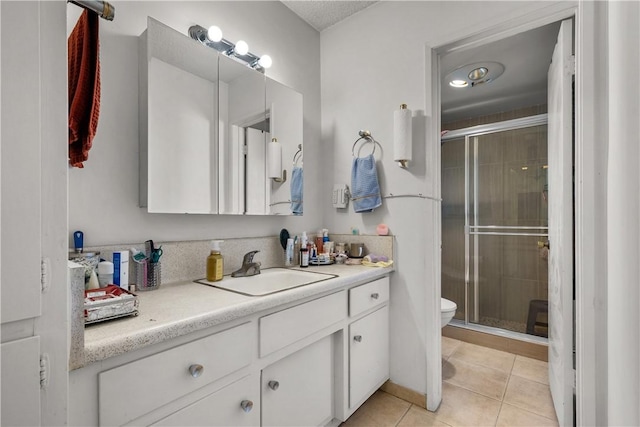 bathroom featuring toilet, tile patterned flooring, a shower with door, and vanity