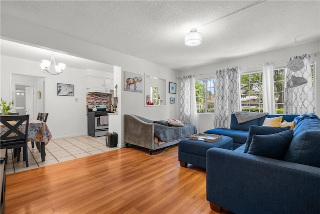 living room with an inviting chandelier, a textured ceiling, and light hardwood / wood-style flooring