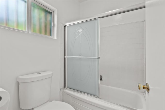 bathroom featuring bath / shower combo with glass door and toilet