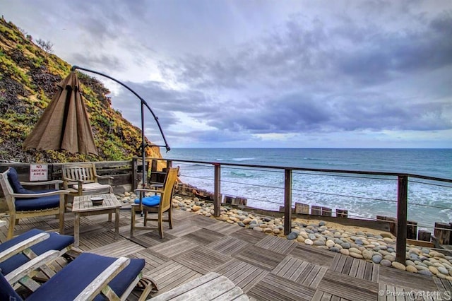 wooden terrace featuring a water view and a view of the beach