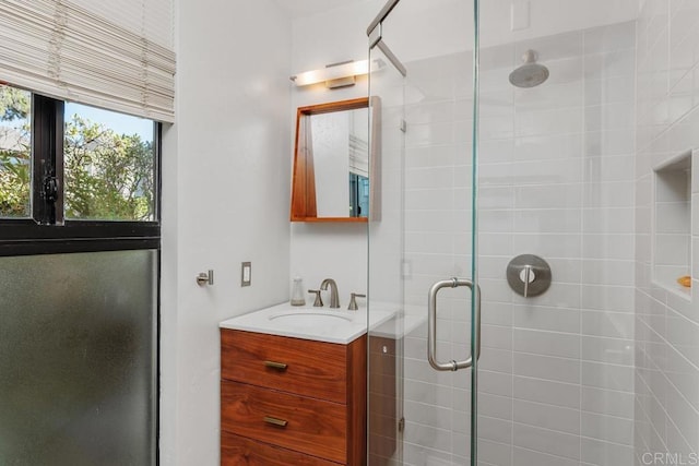 bathroom featuring a shower with door and vanity