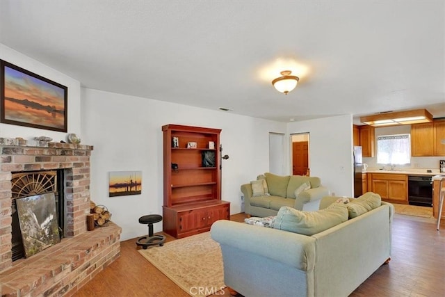 living room featuring light hardwood / wood-style floors, sink, and a brick fireplace