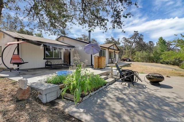 rear view of property featuring a patio and an outdoor fire pit