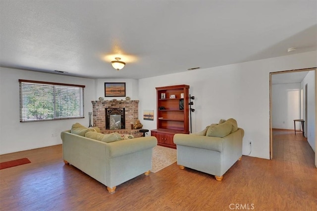 living room featuring wood-type flooring, a textured ceiling, and a fireplace