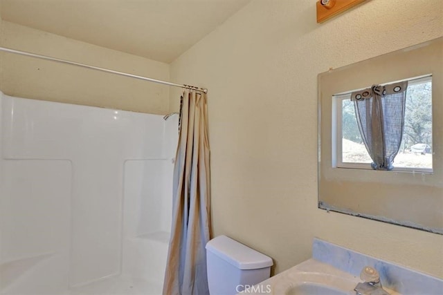 bathroom with a shower with curtain, sink, and toilet