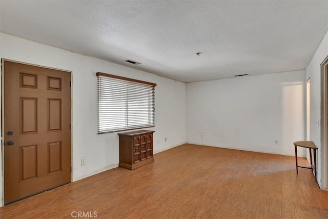 foyer entrance with a textured ceiling and light wood-type flooring