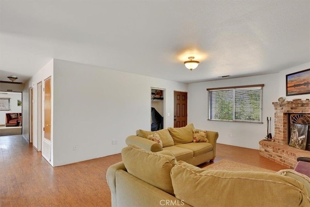 living room featuring wood-type flooring, a textured ceiling, and a fireplace