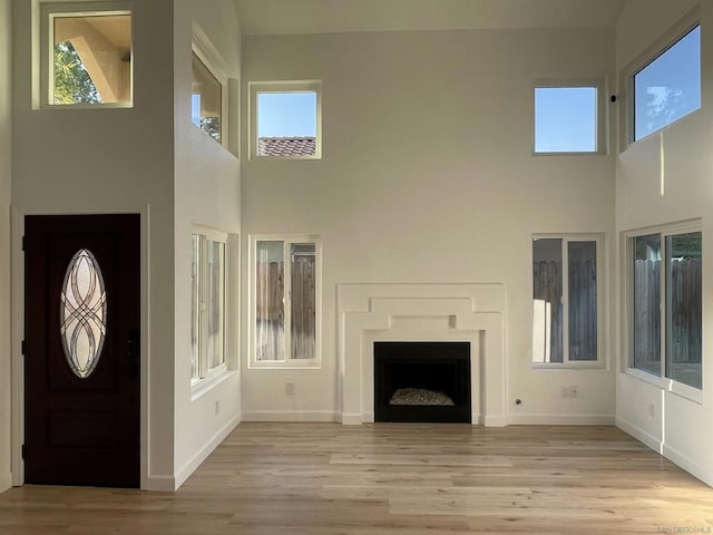 unfurnished living room featuring light hardwood / wood-style flooring and a high ceiling