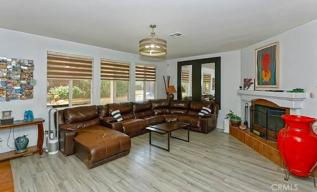 living room featuring a tiled fireplace and light hardwood / wood-style flooring