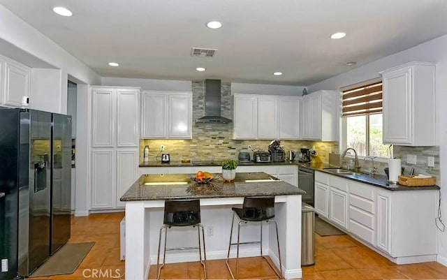 kitchen with white cabinets, a kitchen island, wall chimney exhaust hood, and black appliances