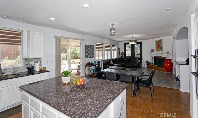 kitchen featuring sink, dark tile patterned floors, a center island, white cabinets, and dark stone counters