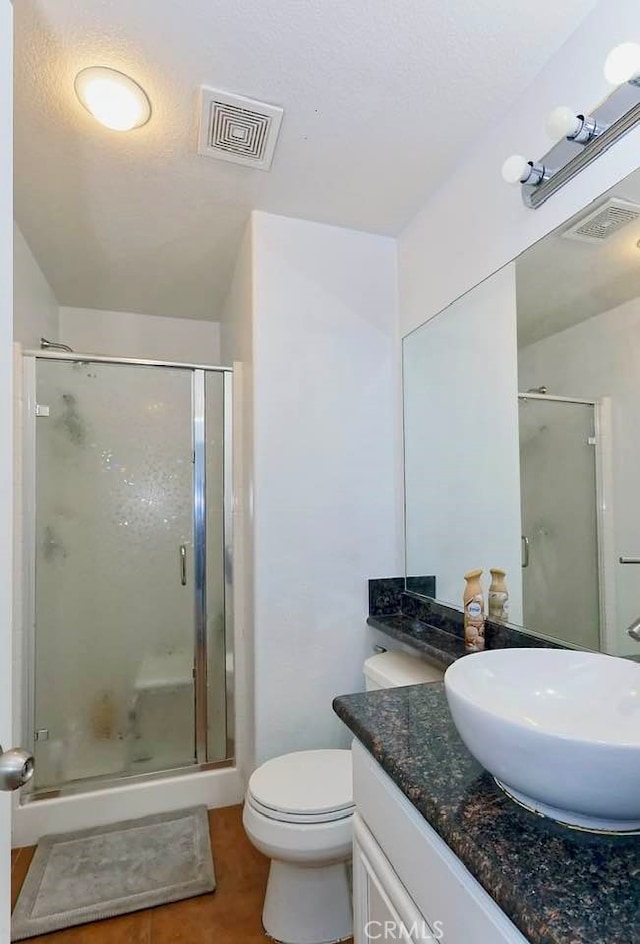 bathroom featuring a shower with door, vanity, a textured ceiling, and toilet