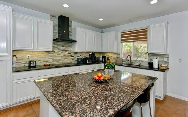 kitchen featuring wall chimney exhaust hood and white cabinets