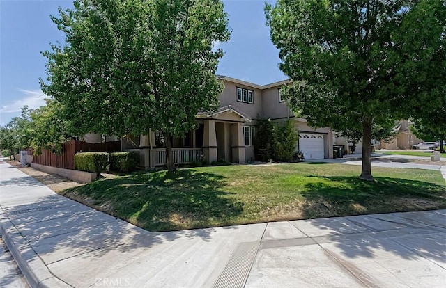 view of property hidden behind natural elements featuring a front yard, fence, concrete driveway, and stucco siding