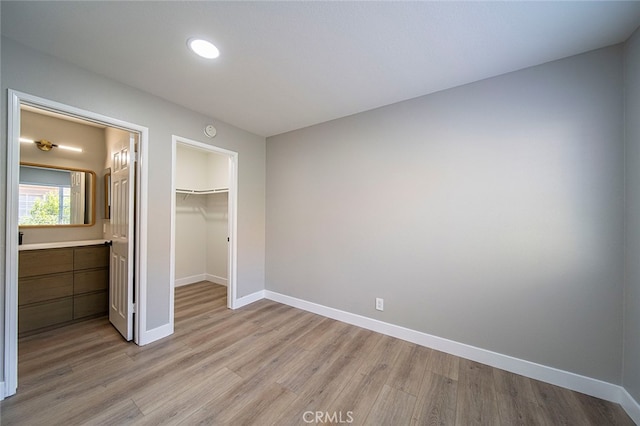 unfurnished bedroom with a spacious closet, light hardwood / wood-style flooring, and a closet