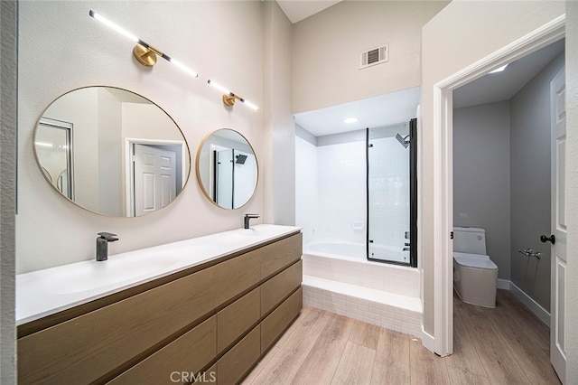 full bathroom featuring vanity, tiled shower / bath combo, wood-type flooring, and toilet