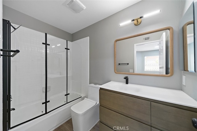 full bathroom with vanity, toilet, wood-type flooring, and enclosed tub / shower combo