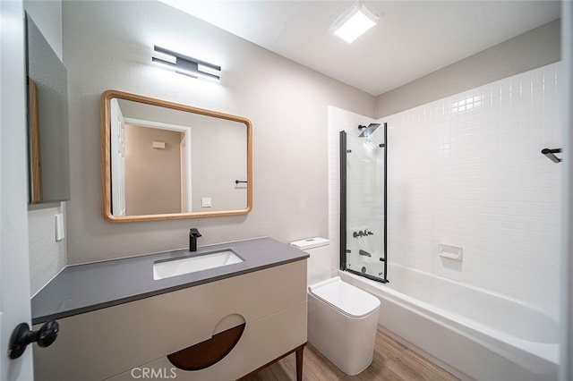 full bathroom featuring tiled shower / bath, vanity, hardwood / wood-style floors, and toilet