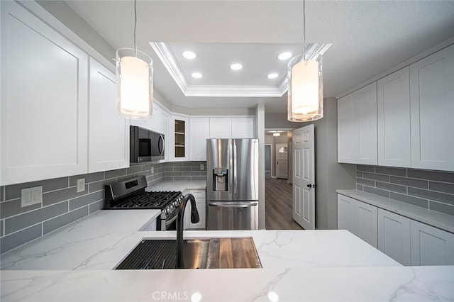 kitchen featuring light stone counters, appliances with stainless steel finishes, decorative light fixtures, and backsplash