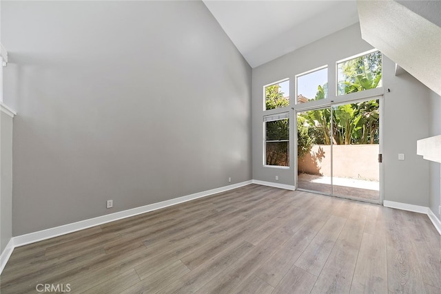 unfurnished living room with light hardwood / wood-style floors and high vaulted ceiling