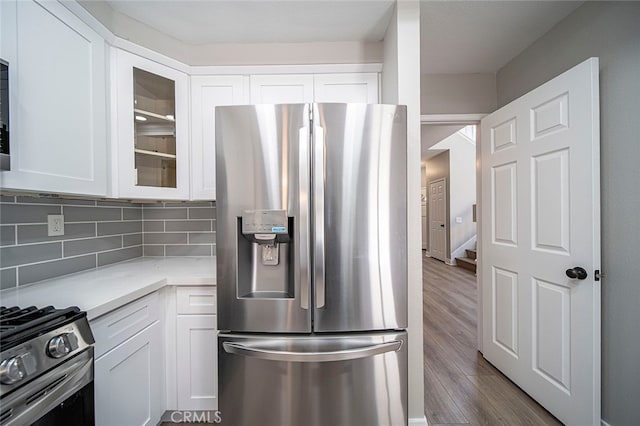 kitchen featuring appliances with stainless steel finishes, decorative backsplash, white cabinetry, and hardwood / wood-style flooring