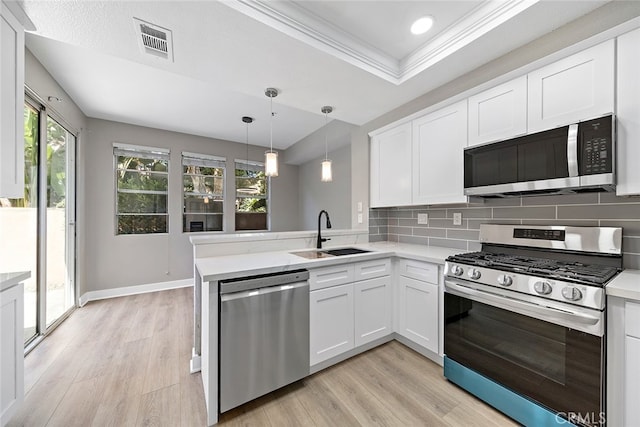 kitchen featuring kitchen peninsula, appliances with stainless steel finishes, white cabinetry, light hardwood / wood-style floors, and sink